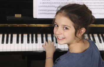 Kleines Mädchen sitzt am Klavier