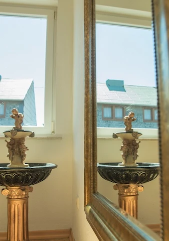 Ein Brunnen vor einem Spiegel. Detailansicht in der Musikschule Kaisers Esch.