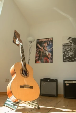 Eine Akustikgitarre auf einem Gitarrenständer in einem sonnendurchfluteten Raum.