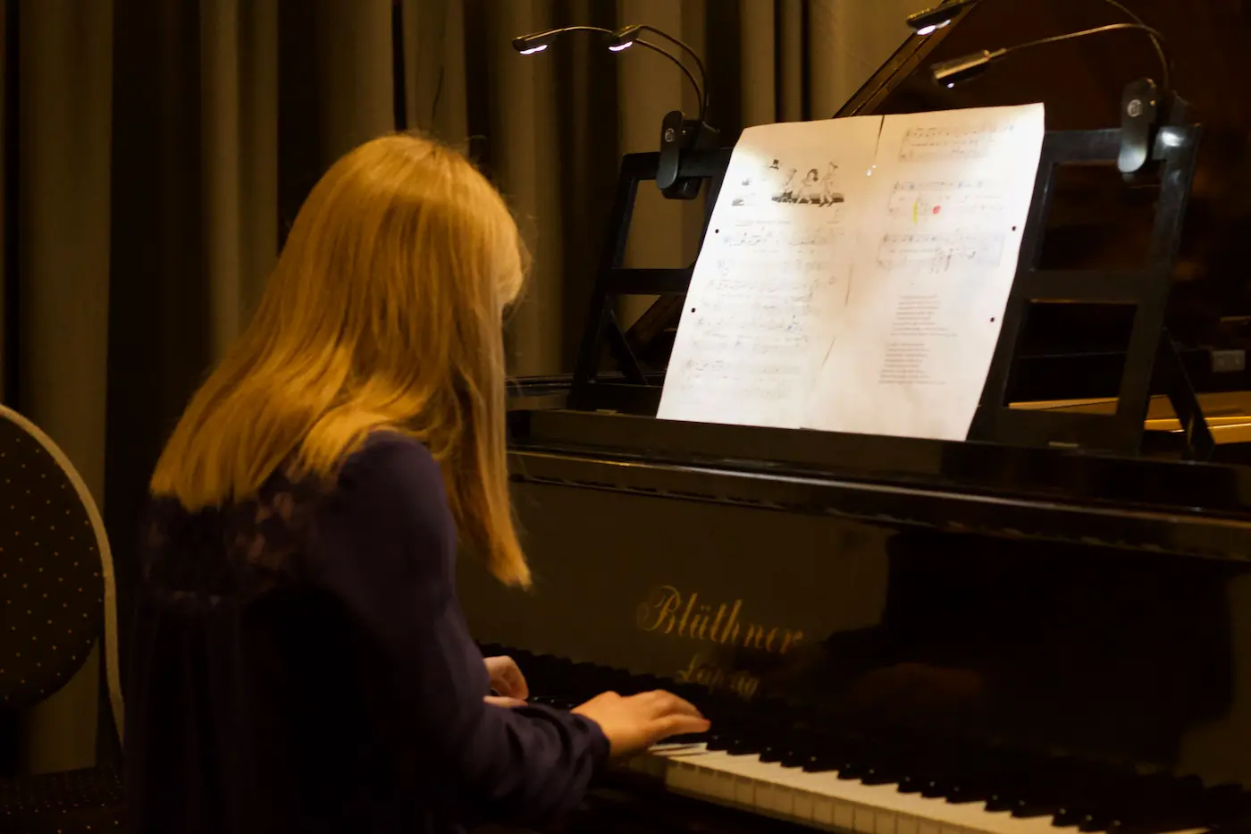 Klavierschülerin sitzt am Klavier und spielt von einem Notenblatt